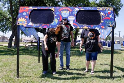 A family look through a pair of giant solar eclipse glasses at Veterans Memorial Park in Dripping Springs, Texas. EPA