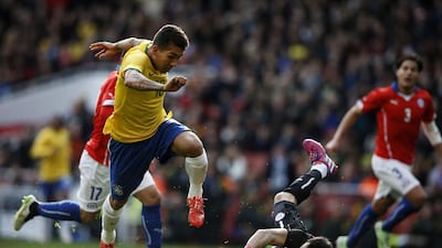 Brazil's midfielder Roberto Firmino, left, takes the ball past Chile's goalkeeper Claudio Bravo, centre, to score the only goal their international friendly at The Emirates Stadium in London on March 29, 2015. Adrian Dennis / AFP
