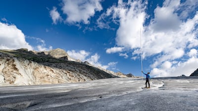 A glaciologist stands beside an eight-metre marker measuring the annual ice melt of the Rhone Glacier, Switzerland. EPA