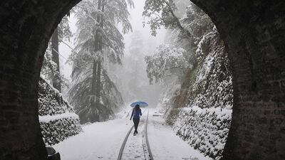 A woman walks along a narrow-gauge railroad track during heavy snowfall in the northern hill town of Shimla. AFP