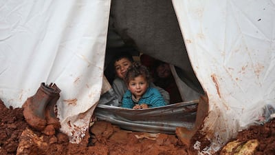 Syrian children sit in their tent look out at the muddy path at the Cordoba camp for internally displaced Persons (IDP), close to Batabu town, along the highway leading to the Syrian Bab al-Hawa border crossing with Turkey, in the northern Syrian Idlib province. Following heavy rain storms, the camp has become water logged, flooding the tents and making the the roads muddy and difficult to maneuvre on. AFP