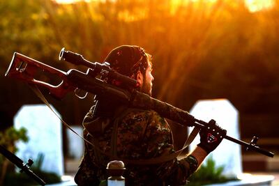 A Syrian Democratic Forces'(SDF) fighter holds a sniper rifle on his shoulder as he attends the funeral of a slain People's Protection Units (YPG) commander in the northeastern city of Qamishli on December 6, 2018. / AFP / Delil SOULEIMAN