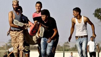 Libyans help a wounded man during clashes outside the office of the Libya Shield pro-government militia in Benghazi. AP Photo