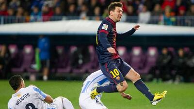 Barcelona's Lionel Messi avoids Malaga's Weligton de Oliveira to have a shot at goal.
