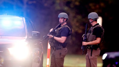 Law enforcement stand at the entrance to Neuse River Greenway Trail parking area after the shooting. AP
