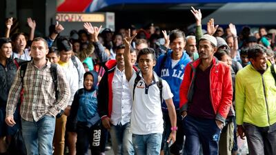 Refugees cheer as they arrive at the main train station in Munich on Sunday September. Sven Hoppe / EPA