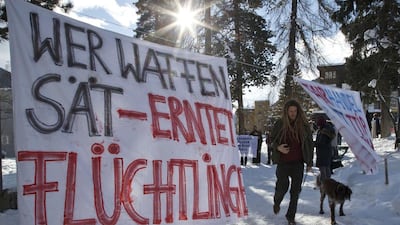 A protest banner reads ‘Arms produce refugees’, at the World Economic Forum in Davos, Switzerland, last year. The annual meeting brings together chief executives, heads of state and economists to discuss issues such as the climate, technology and conflict. Michel Euler / AP Photo.