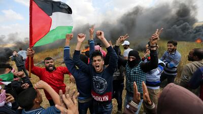 Smoke billows behind a group of Palestinians during a tent city protest along the Israel border with Gaza. Ibraheem Abu Mustafa / Reuters