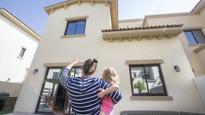 Kirsty Muirhead, with her daughter, points at a hole in the exterior of her home in Mira 1 caused by a chunk of concrete that fell from the roof. Leslie Pableo for The National