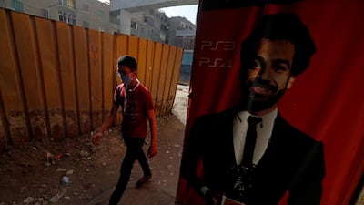 A man wearing a protective face mask walks next to a poster depicting football player Mohamed Salah of Liverpool, amid concerns over the coronavirus disease in Cairo, Egypt. Reuters