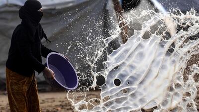A woman empties a basin full of water at Abu Al-Khashab camp in Deir Ezzor. AFP
