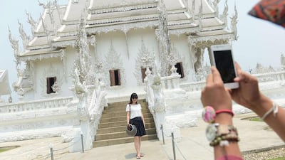 A tourist posing for a picture as she visits the White Temple in Chiang Rai, northern Thailand. Accused of urinating in public, spitting on the street, or kicking a sacred temple bell, free-spending Chinese tourists are receiving a mixed welcome as their soaring numbers help the kingdom's creaking economy. Christophe Archambault/AFP Photo
