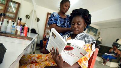 A client has her hair done on August 30, 2016, while reading a book from a small library at the hairdresser’s in Abidjan, Ivory Coast. Sia Kambou / Agence France-Presse