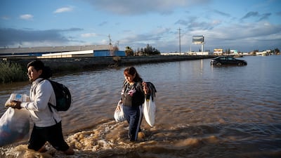 Angeles Molina carries belongings from her home flooded by the overflowing Bear Creek in Merced. AP