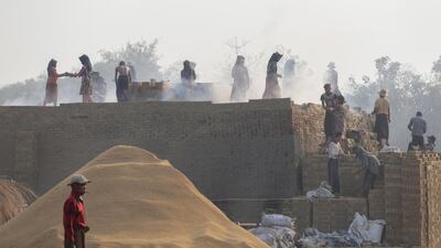 Myanmar laborers relay bricks while working among smoke rising from a brick kiln at a factory on the outskirts of Yangon, Myanmar. EPA