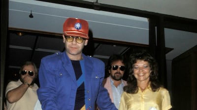 Elton John, wearing red shorts, a blue jacket and red baseball cap, with Renate Blauel following their wedding on February 14, 1984. Getty Images