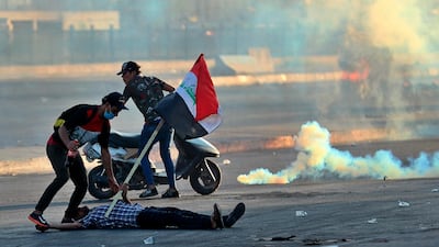A protester falls injured while holding a national flag during a demonstration in Baghdad, Iraq. AP