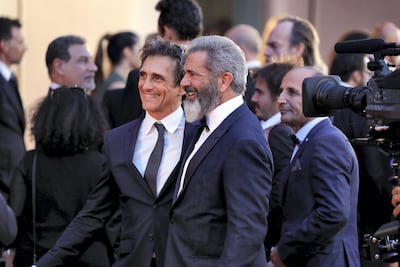 Sarikaya behind Mel Gibson on the red carpet at Venice in 2016. Getty