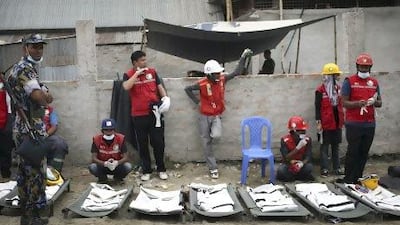 Health volunteers wait next to body bags as they prepare to extract more dead bodies from the garment factory building which collapsed in Savar, near Dhaka.