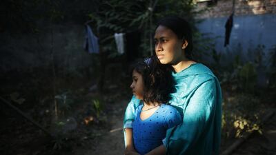 Jesmine Akhter, who was rescued from the rubble of the collapsed Rana Plaza building, stands in front of her slum house with her daughter Zarin, in Savar. Akhter is unable to work due to a spinal injury sustained from the accident last year.