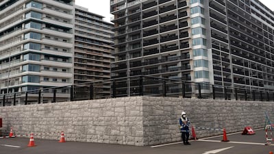 A guard stands in front of apartment buildings at the athletes' village for the Tokyo 2020 Olympics in Tokyo on Monday. AP