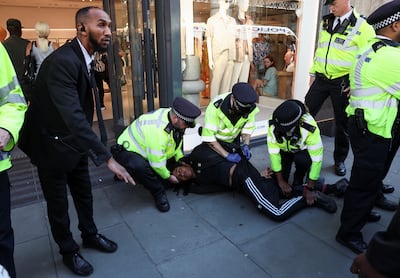Police officers detain a person as disruptors target shops during a shoplifting spree flash mob on Oxford Street in London. Reuters