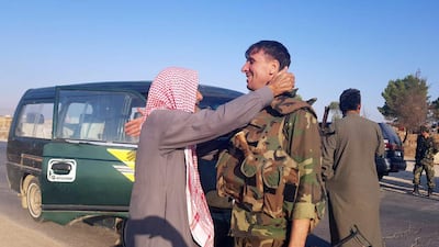 A man greets a Syrian army soldier in the town of Tel Tamer in northeast Syria. REUTERS