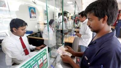 Mohammed Moinudheen Khan, right, from Uttar Pradesh, India, sends money home at the UAE Exchange in Dubai. Satish Kumar / The National