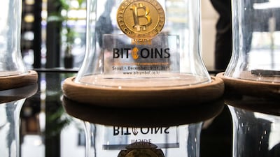 FILE: A gold colored bitcoin token sits on display under a glass cloche inside the offices of La Maison du Bitcoin bank in Paris. Bitcoin is showing no signs of slowing down. Christophe Morin/Bloomberg