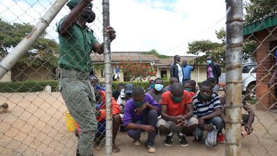 Prisoners kneel behind a gate before their release at Chikurubi Maximum Prison in Harare, Zimbabwe. Three thousand prisoners have been freed from prison to ease the pressure on the country's prisons in view of the pandemic. EPA