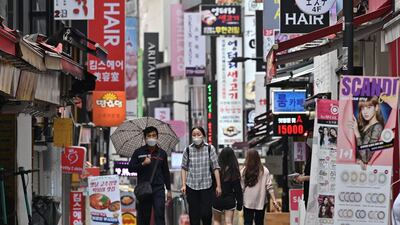 People walk through the Myeongdong shopping district in Seoul. South Korea's central bank slashed its growth forecast predicting the world's 12th-largest economy will shrink more than one percent this year as it braces for a surge of coronavirus infections. AFP