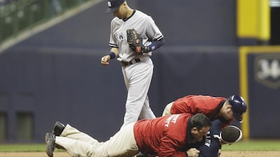 New York Yankees' Derek Jeter jogs past as security tackle a fan who had jumped out of the stands at Milwaukee and ran onto the field to give the shortstop a hug. Jeter announced before the season began that this would be his last in the majors. Mike McGinnis / AFP