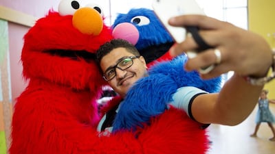Mohammad Khawldeh takes a selfie with Sesame Street characters Grover and Elmo during the launch of Iftah Ya Simsim in Abu Dhabi. (Christopher Pike / The National)