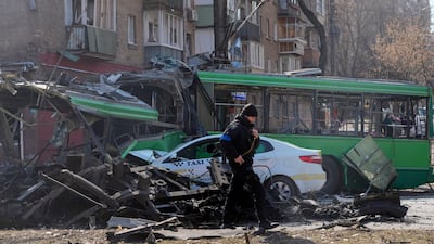 A Ukrainian soldier passes a destroyed a trolleybus and taxi after a Russian bombing attack in Kyiv, Ukraine. AP