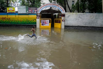 A boys runs across a flooded street outside a school after heavy rainfall in Mumbai. AP