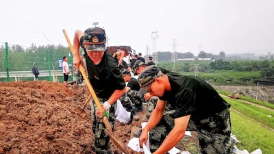 Paramilitary police officers reinforce a lake wall after heavy rain caused severe flooding near Zhengzhou, in China's central Henan province, in which more than 30 people are thought to have been killed with the death toll expected to rise.