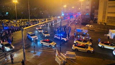 Crowds line the streets as a parade of police cars and taxis enter Al Ras and Naif on Sunday night. Officials played the national anthem and thanked residents for their cooperation after an almost month-long lockdown. The National