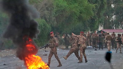 An Iraqi officer directs a soldier's weapon away from anti-government protesters during a demonstration in Baghdad, Iraq. AP