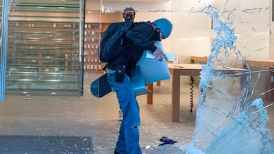 A man takes an iMac through the broken window of the Apple store at the Grove shopping center in the Fairfax District of Los Angeles. AFP