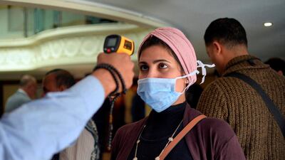 A woman wearing a protective health mask has her body temperature measured at a river boat in Egypt's southern city of Luxor on March 8, 2020. AFP