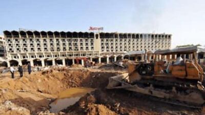 A worker uses a bulldozer to cover the huge crater with earth in front of the devastated Marriott Hotel in Islamabad on September 23, 2008.