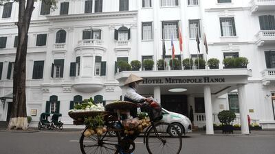 Today: a street vendor pushes her bicycle past the iconic hotel Metropole in Hanoi on January 19, 2017. Photo: AFP
