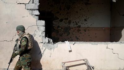A soldier walks by a house damaged during clashes with ISIL fighters in Al-Qasar.