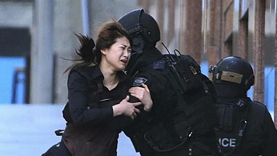 Jieun Bae runs to armed tactical response police officers for safety after she escaped from a cafe under siege at Martin Place in the central business district of Sydney, Australia. Police responding to the deadly hostage crisis in a Sydney cafe underestimated the gunman's threat and should have stormed the building earlier, rather than waiting to act until the gunman had killed a captive, a coroner said on Wednesday, May 24, 2017. Rob Griffith / AP Photo