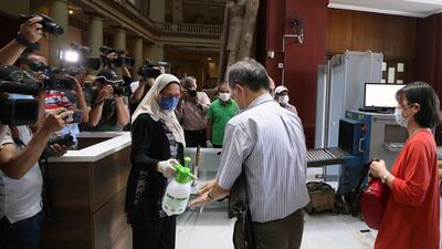 A worker sprays disinfectant as people visit the Museum of Egyptian Antiquities. EPA