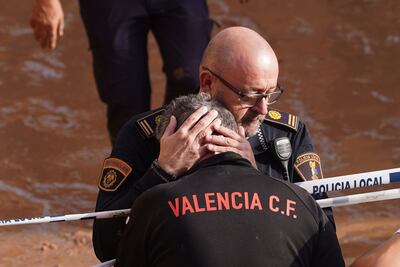 Members of the local police react to the news that one of their colleagues died in the floods in Valencia. AP
