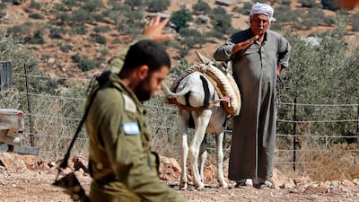 A Palestinian farmer watches an Israeli soldier walk past him during a demonstration against the closure of agricultural roads leading to the olive fields in the village of Kafr Thulth, east of Qalqilya in the occupied West Bank. AFP