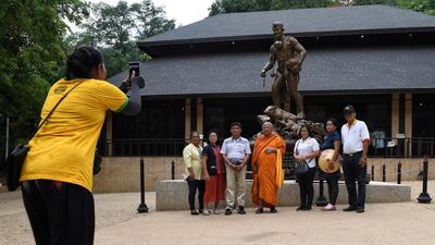This picture taken shows visitors posing for photos in front of a statue of Saman Gunan, the Thai diver who died during the efforts to rescue the boys and their coach. AFP