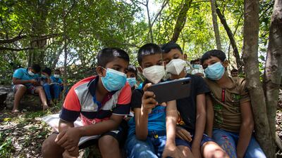 Sri Lankan children share a smartphone to receive their online lessons on a mountaintop in a forest reserve in Meegahakiwula, Sri Lanka. AP