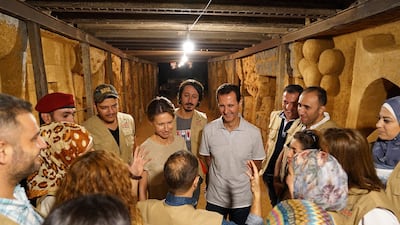 Bashar Al Assad, centre, Syria's president at the time, and his wife Asma, meet artists sculpting on the walls of a tunnel formerly used by rebel fighters in Jobar, on the outskirts of Damascus, in 2018. AFP